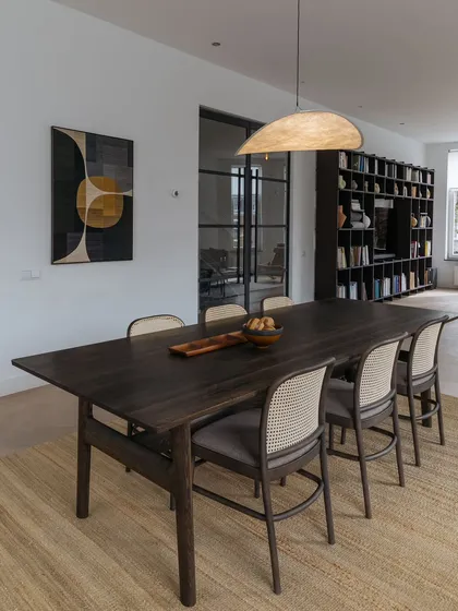 The dining room is a study in contrasts, with a dark, minimalist dining table from Time & Style juxtaposed with a Brutalist oak sideboard. The space is unified by a neutral color palette and warm wooden tones.