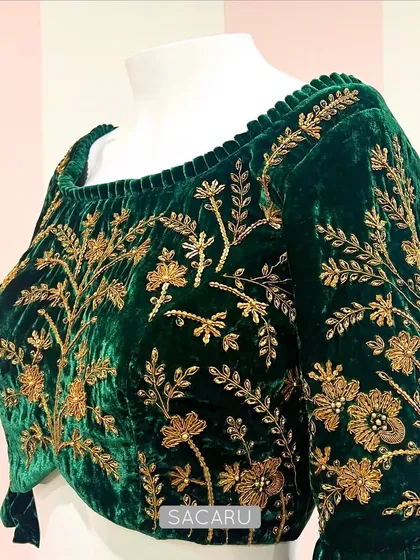 The timeless combination of emerald green velvet and intricate gold zardosi embroidery. This blouse features a classic floral vine motif, making it a treasured piece for any wardrobe.