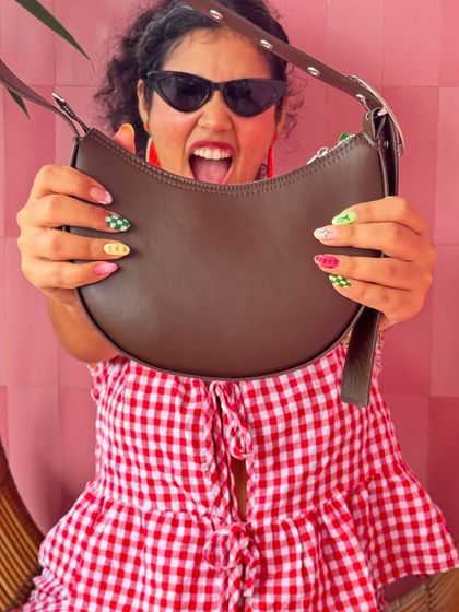 A close-up on the details. This shot highlights my fun, mismatched nails and the texture of the bag, showing that every element of my look is considered.