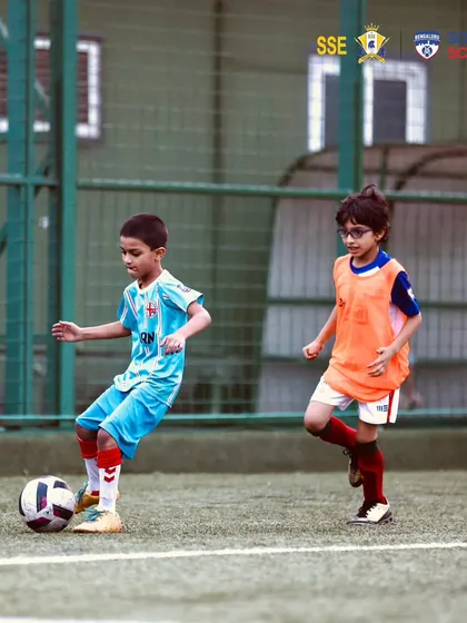 A player in an orange bib dribbling past a defender.