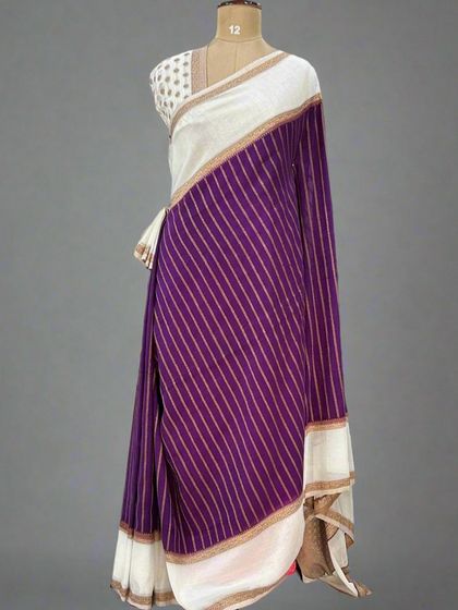 A beautiful semi-wrinkle crepe saree with a white gap border and antique zari weaving, seen here in a purple and white combination on a mannequin.