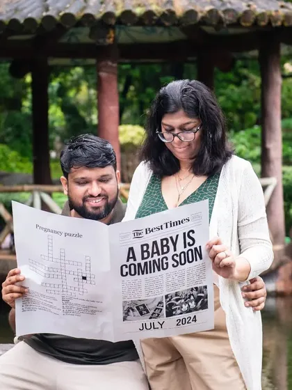 A playful take on their newspaper announcement, with the dad-to-be reading the "news" while his partner looks on with a smile.