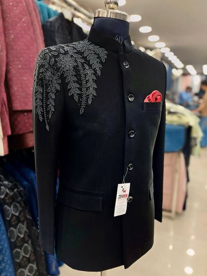 A black Jodhpuri suit with subtle grey leaf embroidery on the shoulder. The pop of color from the red pocket square adds a touch of personality.