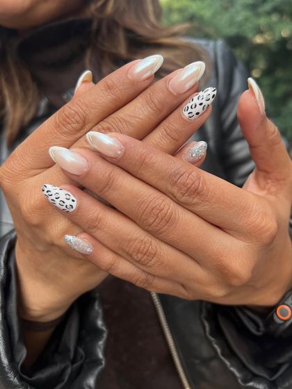 Here, I've mixed different textures and patterns for a modern look. This set combines pearlescent white nails with a classic black-and-white leopard print and a sparkling silver glitter accent nail.