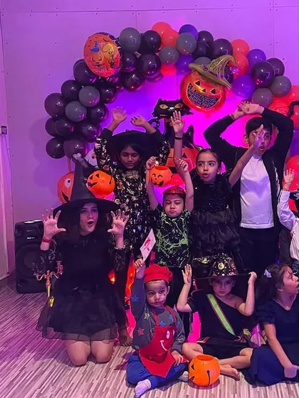 Our little monsters, witches, and superheroes posing for a group photo at the Halloween party. The decorations and spooky lighting really set the mood for a fun time.