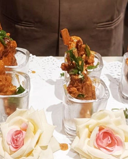 Crispy chicken lollipops served in individual glasses and garnished with fresh roses. This presentation adds a touch of romance and elegance, perfect for weddings or anniversary parties.