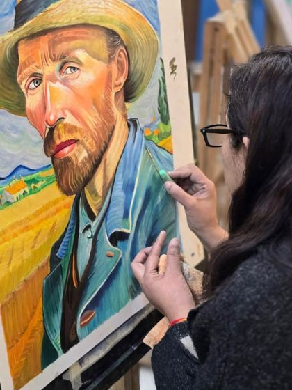An over-the-shoulder view of a student working on her Van Gogh portrait, showing her technique for applying and blending oil pastels.