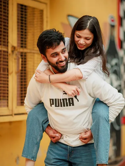Love should be fun. This playful piggyback ride against a vibrant city backdrop in Delhi shows the joyful, carefree side of your relationship. We believe in capturing the real laughter and candid interactions that make your bond unique.