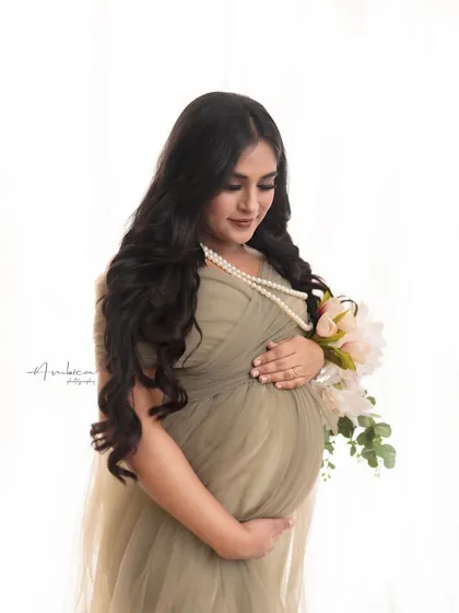 A close-up portrait focusing on her gentle expression as she looks down at her bump. The soft lighting and elegant styling create a serene and loving image.
