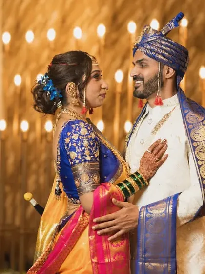 A classic pose against a backdrop of warm lights, showcasing the couple's stunning traditional Maharashtrian wedding attire.