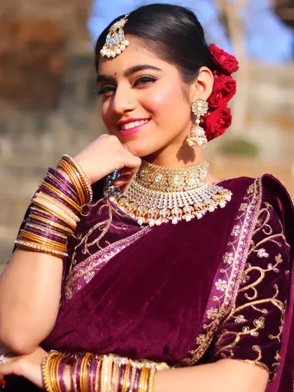 A glamorous reception look featuring a rich velvet saree. The makeup is sophisticated with a focus on sparkling eyes and a confident smile, perfect for celebrating into the night.