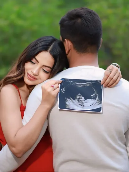 A sweet and creative announcement idea. The mom-to-be leans on her partner's back, holding the sonogram photo as a symbol of the little one who will soon join them.