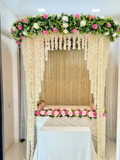 An elegant home Ganpati decoration featuring curtains of jasmine (mogra) flowers. The top and base are adorned with pink and white flowers, creating a fragrant and divine space.