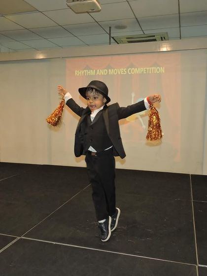 With a top hat and props, this little dancer lights up the stage with his energetic performance and charming costume.