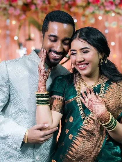 An adorable, happy moment between a couple against a festive, lit background.