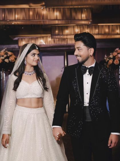 The couple holds hands and shares a loving look as they walk. Their elegant black and white attire and the beautiful lighting create a timeless engagement photo.