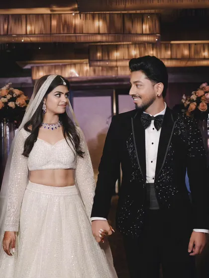 The couple holds hands and shares a loving look as they walk. Their elegant black and white attire and the beautiful lighting create a timeless engagement photo.