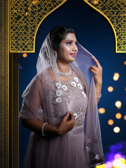This elegant studio portrait showcases a beautiful mauve lehenga, with the sheer dupatta gracefully draped over her head. The pose is classic and poised, highlighting the floral embroidery on the blouse and the sparkling diamond necklace.