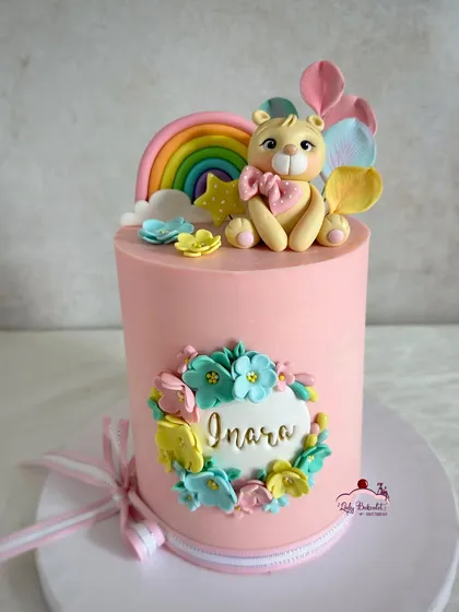 So un-bear-ably cute! A tall pink cake with a floral wreath and an adorable, hand-sculpted teddy bear topper holding a star wand.