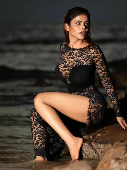 A seated pose on the rocks, blending the elegance of the lace dress with the rugged natural environment. This contrast creates a visually compelling fashion photograph.