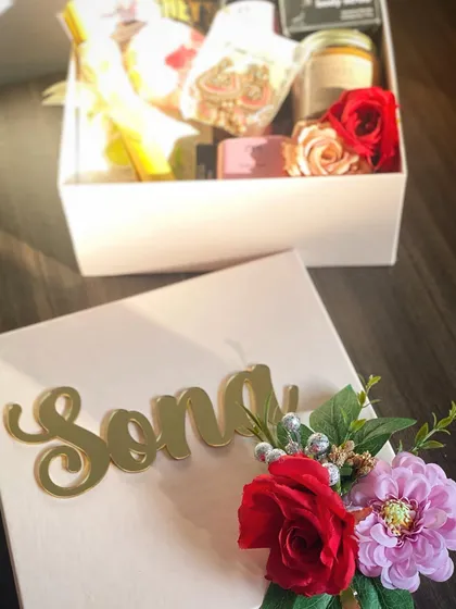 Gifting is an emotion. This beautifully crafted custom gift box features an acrylic name tag and a floral arrangement, making it a truly personal and memorable present.