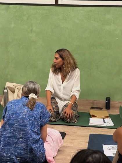 An intimate moment of guidance. Our instructor connects with a participant during a late-night stillness workshop, offering personalized support on their journey to deep rest.