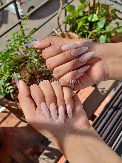 Long stiletto nails with a soft pink base and a reflective top coat that gives them a beautiful shimmer.