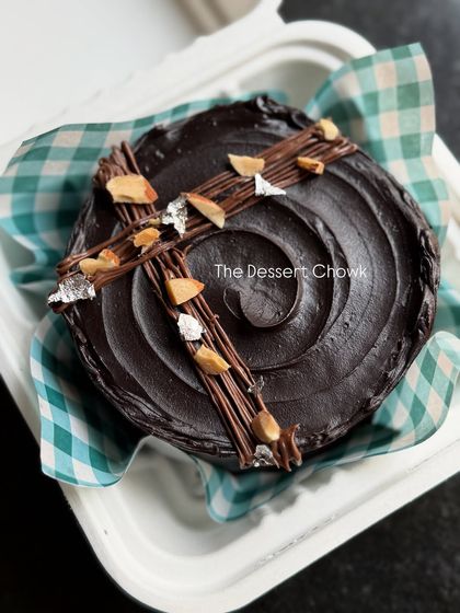 A mini bento brownie cake, decorated with a chocolate swirl and toasted almonds. It's a perfect single-serving treat for when you're craving something rich and chocolatey.