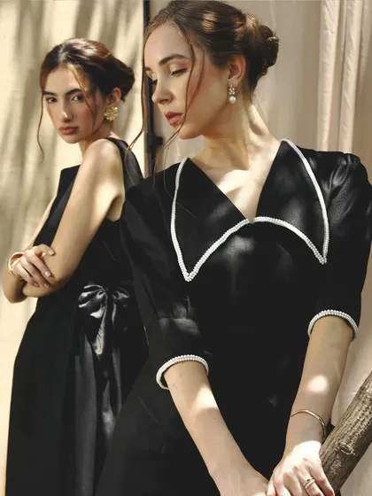 Another angle of the two models in black. This shot highlights the clean lines of the makeup and the elegant, coordinated styling.