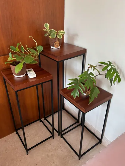 Routine plant check-ups are a joy. Here, we've arranged a few small potted plants on nesting tables, a simple styling touch that brings life and personality to a corner of a home.