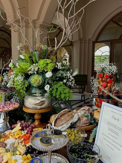 The grazing table in all its glory, with lush floral arrangements and a menu detailing the decadent offerings.