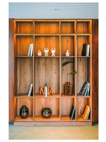 Another view of the integrated bookshelf, showcasing the warm wood tones and thoughtful backlighting that highlights the displayed books and decor.