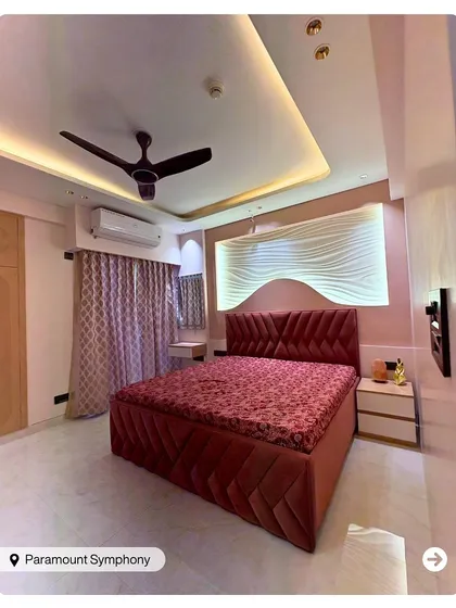 This bedroom features a tufted red velvet bed and a 3D wave-patterned, backlit headboard wall. The design is bold, modern, and luxurious.