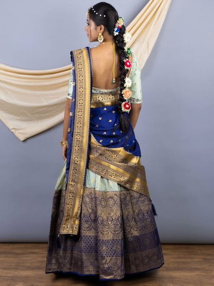 The back view of the Pattu lehenga, showing the traditional braid adorned with flowers and the elegant drape of the silk voni (dupatta).