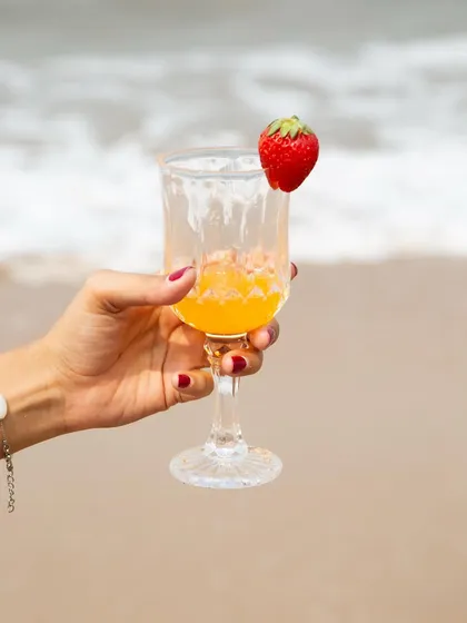 A detailed product shot that still tells a story. The hand holding a garnished drink against the ocean backdrop feels both luxurious and relaxed, ideal for showcasing accessories, nail polish, or beverages.