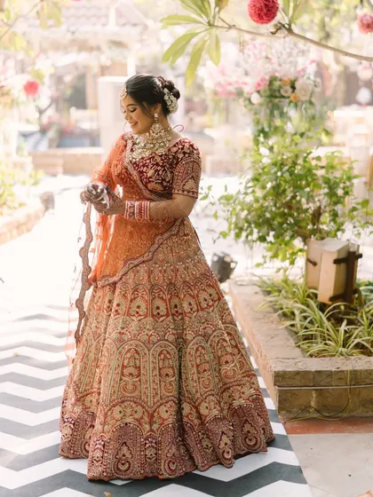 A quiet moment captured. The soft, natural light highlights the beautiful details of her makeup and the intricate embroidery of her lehenga.