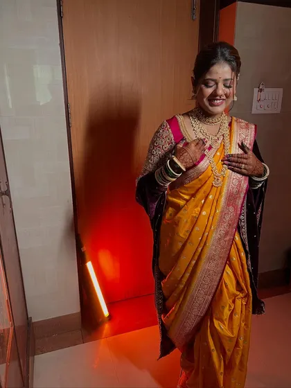A full-length shot of a happy bride in her yellow and purple Paithani saree, showing the complete traditional look with perfect draping.