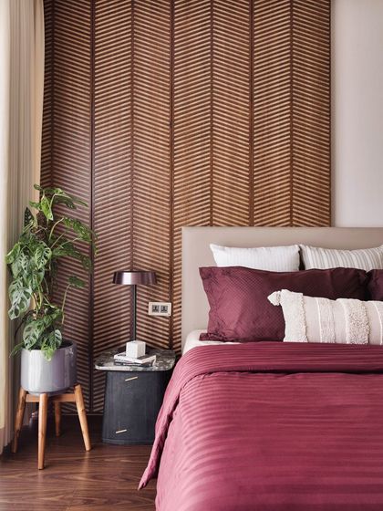 The combination of the wood headboard, dark bedside table, and lush green plant creates a balanced and harmonious composition in the guest bedroom.