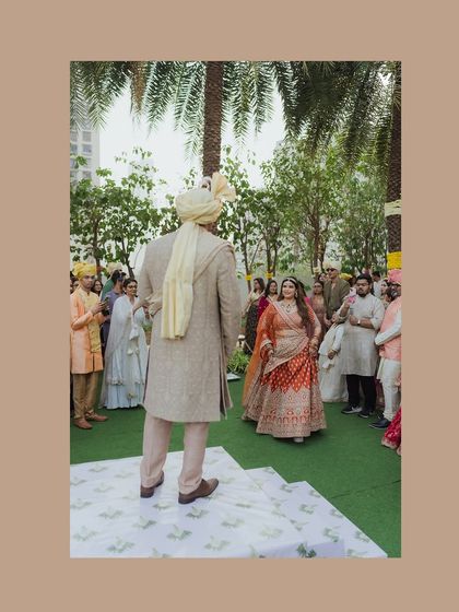 The bride walks towards the groom during the ceremony, a moment of beautiful anticipation. The outdoor setting with guests looking on creates a lovely, communal feel.
