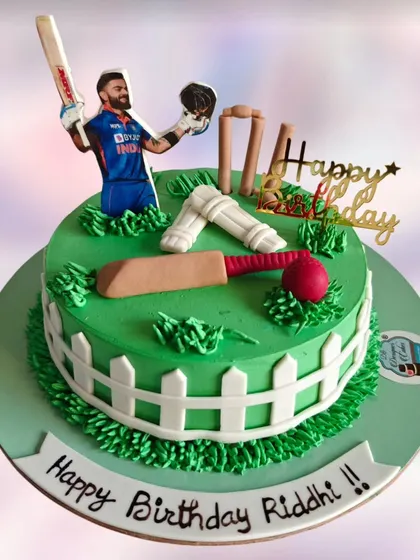 Another cricket-themed cake, this one featuring Virat Kohli. The green field, wickets, and bat are all crafted to create the perfect pitch for a cricket fan's celebration.
