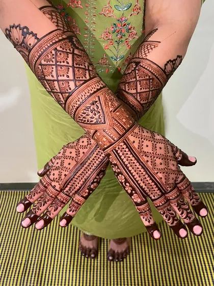 A full-coverage bridal mehendi with a focus on geometric and jaal patterns. The crisscross design on the back of the hands is a modern classic.