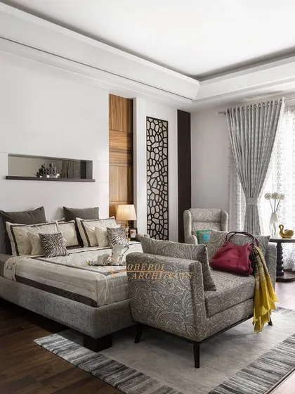 An elegant contemporary bedroom featuring shades of grey, patterned furniture, and a unique jali screen partition for added texture.
