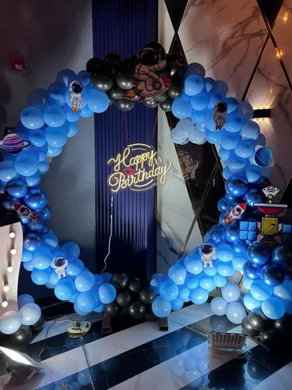 A circular balloon arch in blue and black creates a portal to a space adventure for this 7th birthday party.