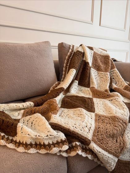 Another angle of the brown and white checkered throw, highlighting the intricate stitch work and the soft, inviting texture of the yarn.