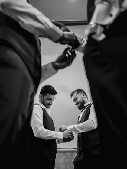 A creative, low-angle black and white shot of the groom and his groomsmen getting ready. The composition is unique and tells a story of camaraderie.
