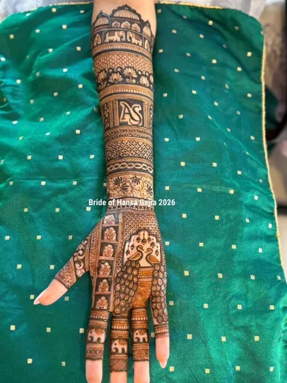This design is filled with grace and personal touches. The elegant peacock on the palm symbolizes beauty, while the personalized initials woven into the arm make the traditional design uniquely hers.