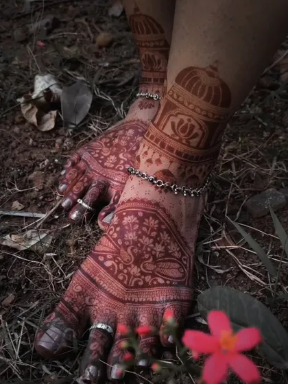 An artistic shot of a bridal foot mehndi design, showing the rich stain against the earth.