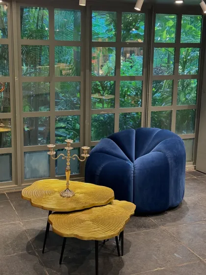 Another scene from our exhibition, showcasing a plush blue velvet armchair paired with our unique, tree-ring inspired coffee tables in a vibrant yellow finish.