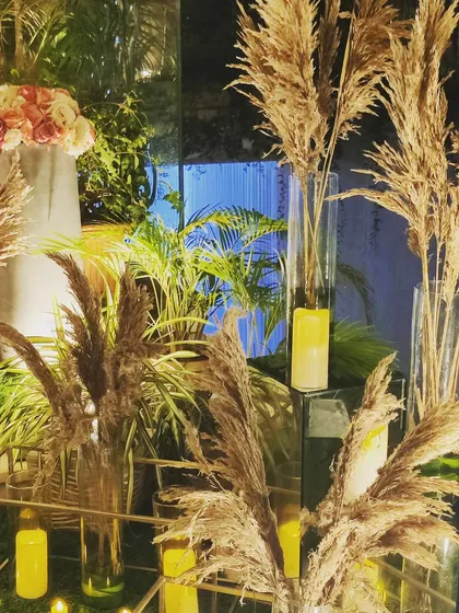 A play of light and shadow with pampas grass and mirrored pedestals. This setup uses reflections to amplify the warm glow of the candles, creating a modern and glamorous ambiance.