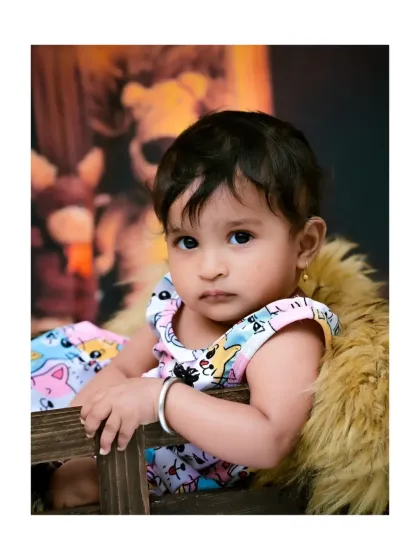 A beautiful close-up portrait from a jungle-themed session. This shot focuses on the baby's sweet, serious expression and her adorable, colorful outfit.